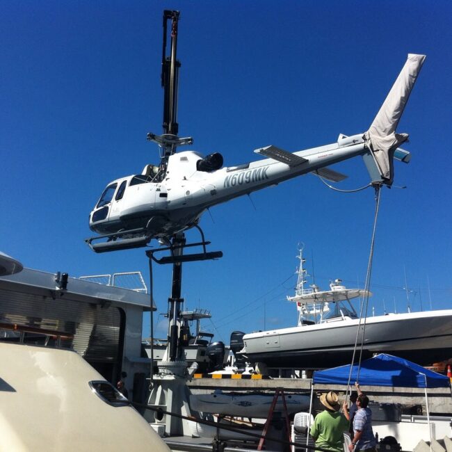 Private Helicopter craned off a superyacht undergoing servicing